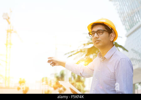 Porträt eines lächelnden indischen männlichen Auftragnehmer Ingenieur mit Schutzhelm auf einem Kran auf Baustelle Stockfoto