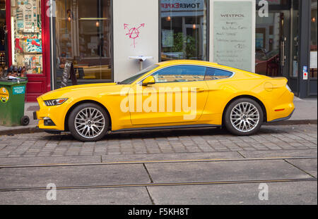 Wien, Österreich - 4. November 2015: Helles Gelb Ford Mustang 2015 Auto steht auf der Straße, Stadt-Seitenansicht. Legendäre Sport-ca Stockfoto