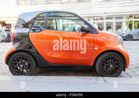 Wien, Österreich - 4. November 2015: Helle rote und schwarze Smart Fortwo W453 Auto steht auf der Straße, Stadt-Seitenansicht Stockfoto