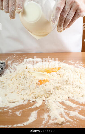 Ein Bäcker, eine saure Sahne in einen Haufen von Mehl gießen. Teig machen für ungarische Kuchen. Serie. Stockfoto