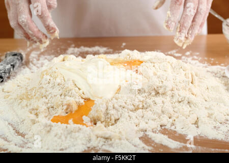 Ein Bäcker, mischen, Mehl, saure Sahne und Eiern. Teig machen für ungarische Kuchen. Serie. Stockfoto