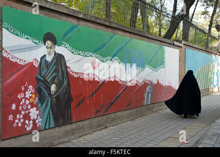 Teheran, Iran. 4. November 2015.veiled Iranerin, Spaziergänge Vergangenheit ein Ajatollah Khomeini Bild gemalt an der Wand des ehemaligen US-Botschaft in Teheran, Iran.Thousands der Iraner die amerikanische Flagge verbrannt und skandierten Parolen Mittwoch, wie sie den Jahrestag der Beschlagnahmung der US-Botschaft in Teheran von Studenten vor 36 Jahren markiert Stockfoto