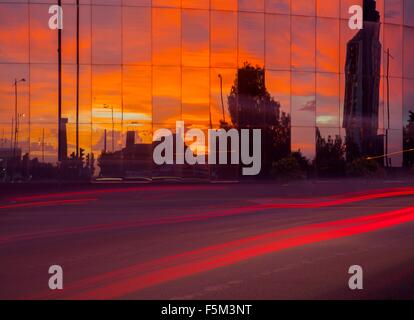 Autobahn Ampel Trails und Glas fronted Bürogebäude bei Sonnenuntergang Stockfoto