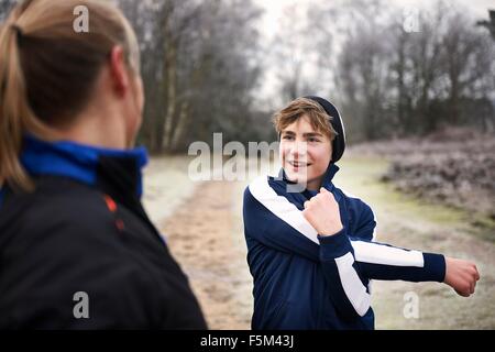 Teenager Dehnung Arm, Blick auf Mutter lächelnd Stockfoto