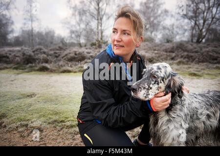 Reife Frau kauert sich streicheln Hund wegsehen Stockfoto