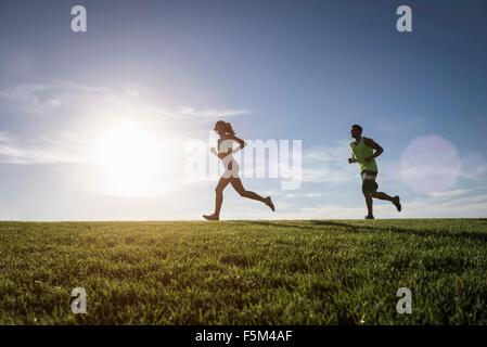 Sonnendurchflutetes Mann und Frau im Park laufen Stockfoto