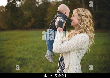 Mitte Erwachsene Frau hält Baby Sohn im Feld Stockfoto