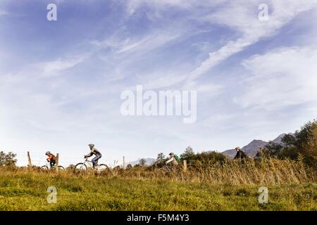 Seitenansicht der Familie Reiten Fahrräder auf Ackerland Stockfoto