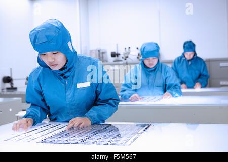 Arbeitnehmerinnen, die Inspektion Flex-Schaltungen in flexible Elektronik Fabrik Reinraum Stockfoto
