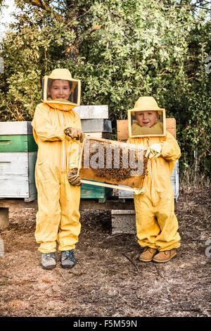 Porträt der jungen Mädchen und jungen im Halterahmen Bienenstock voller Bienen Imker-Kleid Stockfoto