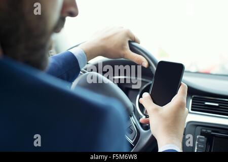 Junger Geschäftsmann Lektüre Smartphone im Auto Stockfoto