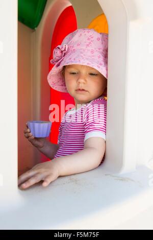 Weiblichen Kleinkind blickte von Playhouse-Fenster Stockfoto