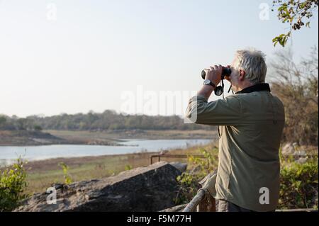 Senior woman Blick durch ein Fernglas am Fluss Kafue Nationalpark, Sambia Stockfoto