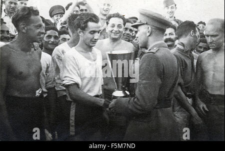Ein britischer Offizier stellt eine Tasse belgische Kriegsgefangene nachdem sie britische Kriegsgefangene bei Fußballspielen geschlagen hatte. Stalag V111A, Deutschland 1944 Stockfoto