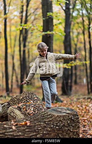 Mädchen, balancieren auf Baumstamm im herbstlichen Wald Stockfoto