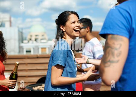 Weibliche und männliche Freunde lachen und plaudern bei Dach-barbecue Stockfoto