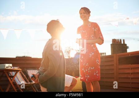 Mann schlägt Frau auf Dachterrasse, Sonnenuntergang im Hintergrund Stockfoto