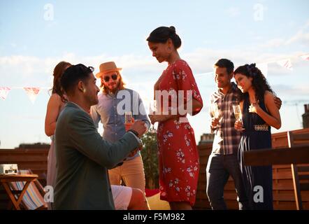 Mann schlägt Frau auf Dachterrasse, Sonnenuntergang im Hintergrund Stockfoto