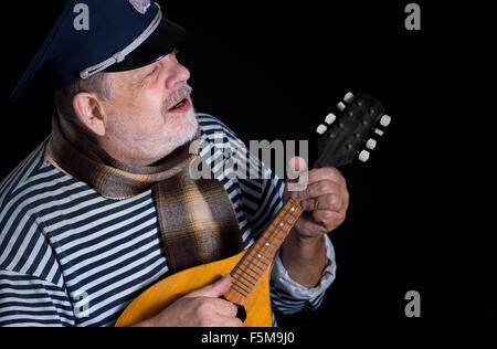 Senior woman in gestreiften Weste und Tröster mit Mandoline zu spielen und Singen Musik Stockfoto