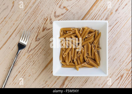 Schüssel mit Vollkorn-Penne-Nudeln. Von oben gesehen. Stockfoto