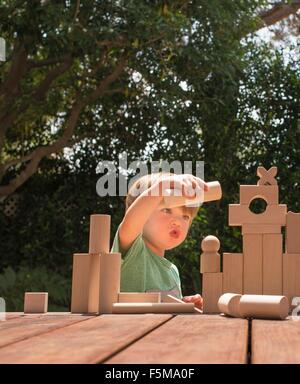 Kleiner Junge spielt mit Holzbauklötzen im Garten Stockfoto