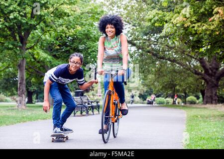 Skateboard junge Mütter Fahrrad im Park festhalten Stockfoto