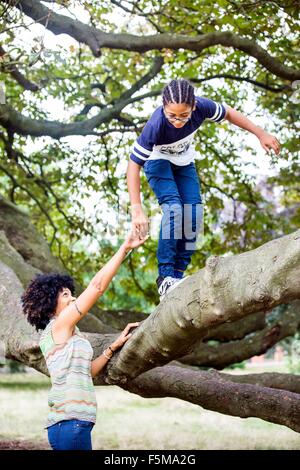 Reife Frau Söhne Hand haltend, während Park Ast klettern Stockfoto