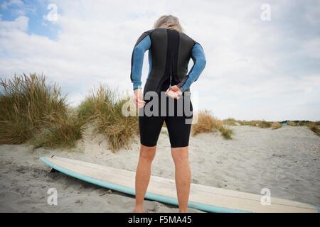 Ältere Frau anziehen Neoprenanzug, Rückansicht Stockfoto