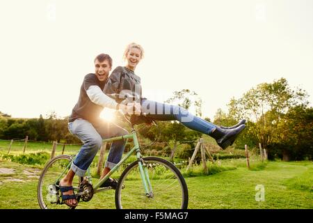 Junge Frau sitzt am Fahrradlenker Freunde Stockfoto