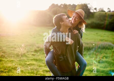 Junger Mann mit Freundin eine Huckepack im ländlichen Bereich Stockfoto