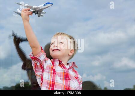 Junge hält Spielzeugflugzeug vor Haus Fenster Stockfoto