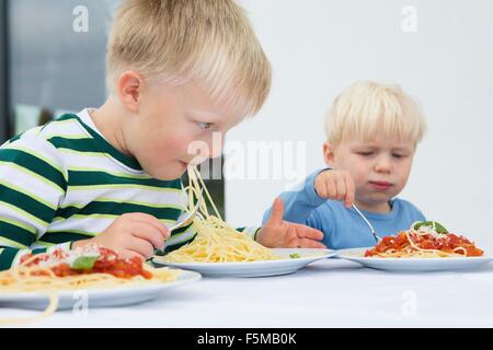 Junge und Kleinkind Bruder Essen Spaghetti auf Terrasse Stockfoto