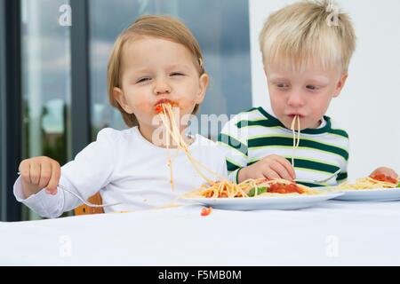 Junge und weibliche Kleinkind Essen Spaghetti auf Terrasse Stockfoto