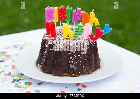 Geburtstagstorte mit Kerzen auf Gartentisch Stockfoto