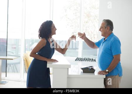 Ältere Mann und Frau Anhebung ein Glas Weißwein über Küchentheke Stockfoto