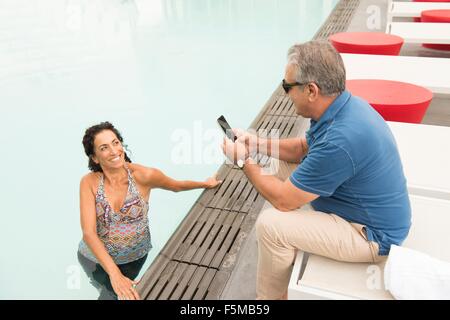 Senior woman fotografiert Frau mit Smartphone von am Pool Stockfoto