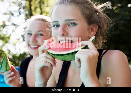 Zwei Mädchen im Teenageralter Essen Wassermelone Scheiben im Garten Stockfoto