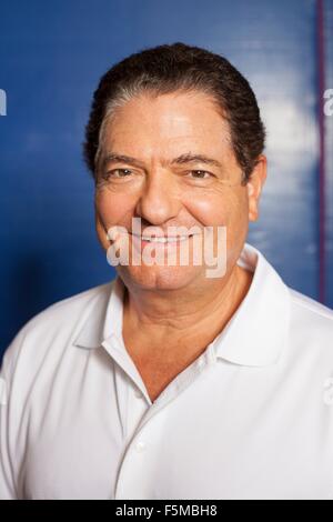 Porträt des älteren Menschen (Tischtennisspieler) trägt weißes Polo-Hemd Blick auf die Kamera zu Lächeln Stockfoto