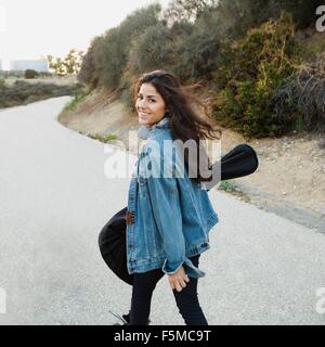 Junge Frau, die die Gitarre über Schulter schaut in die Kamera Lächeln, Woodland Hills, Kalifornien, USA Stockfoto