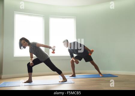 Älteres Paar auf Yoga-Matten-Training mit Hanteln Stockfoto