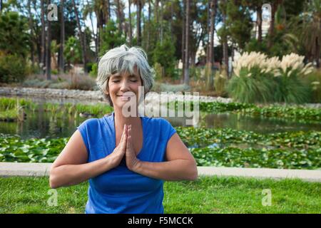 Reife Frau meditieren im park Stockfoto