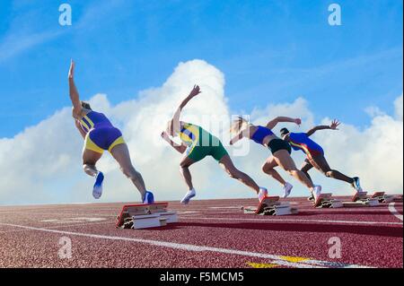 Vier weibliche Athleten auf Leichtathletik-Laufbahn verlassen Startblöcken, Rückansicht Stockfoto