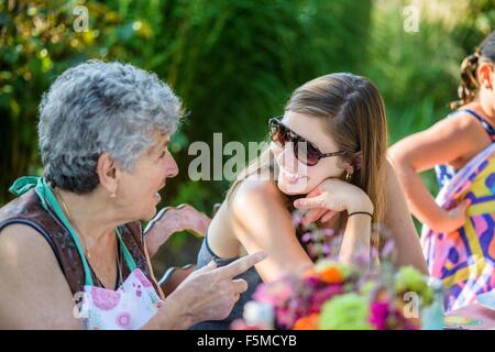 Mitte Erwachsene Frau im Gespräch mit älteren Frau im Garten Stockfoto