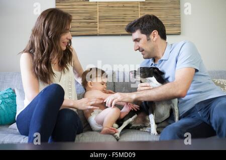 Familie mit Baby junge auf Sofa spielen mit Hund Stockfoto