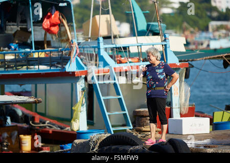 Chinesische Frau durch den Fisch Markt Kai im Hafen von Cheung Chau, Hong Kong. Stockfoto