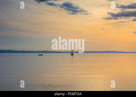 Ein Segelboot ist in Langenargen Deutschland während des Sonnenuntergangs in der Ferne sehen. Den Bodensee. Stockfoto