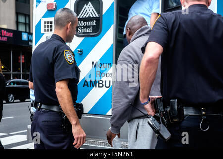 New York City, New York, USA.  11. November 2015: Polizei helfen, einen Mann in einen Krankenwagen zu eskortieren. Stockfoto
