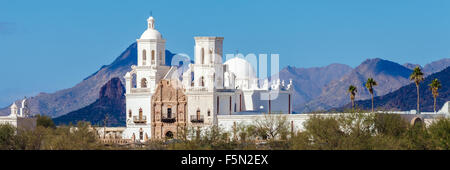 Mission San Xavier del Bac glänzt in der heißen Sonne mit Hügeln im Nordwesten und die blauen Arizona sky einen Hintergrund. Stockfoto