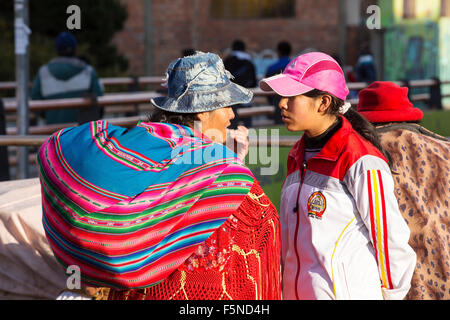Eine einheimische Frau und Tochter auf einem Straßenmarkt in El Alto, La Paz, Bolivien, Südamerika, zeigen die traditionellen und modernen Möglichkeiten des Verbandes Stockfoto