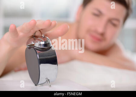 Verschlafene Jüngling schaltet der Wecker. Stockfoto